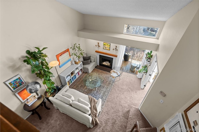 living room with a textured ceiling, carpet floors, vaulted ceiling, and a fireplace with flush hearth