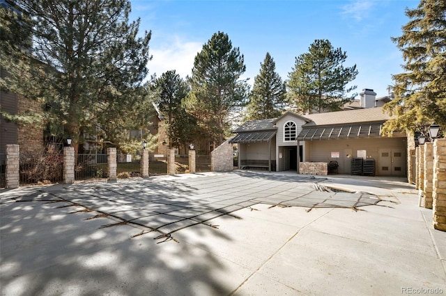 view of front facade featuring a patio, roof with shingles, a chimney, and fence