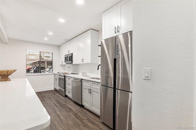 kitchen with a sink, white cabinetry, stainless steel appliances, and dark wood-style flooring