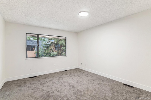 unfurnished room with carpet, a textured ceiling, visible vents, and baseboards