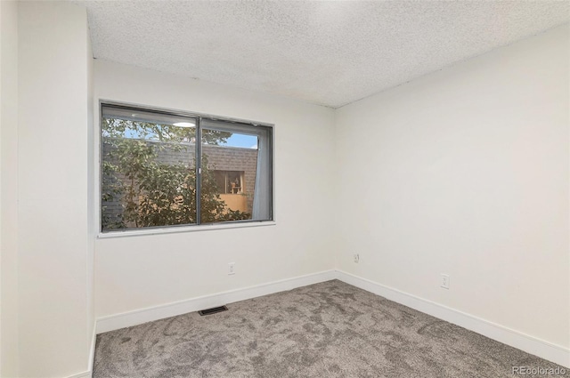 spare room with carpet, visible vents, a textured ceiling, and baseboards