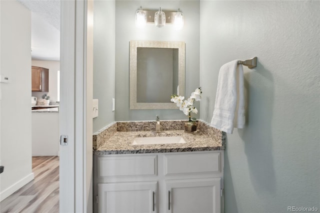 bathroom with wood finished floors, vanity, and baseboards