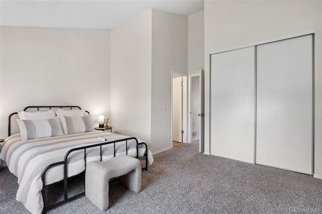 bedroom with carpet floors, baseboards, a towering ceiling, and a closet