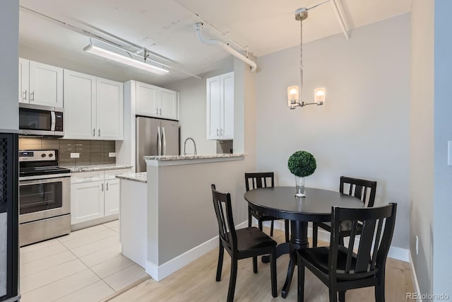 444 17th St Unit 701, Denver, CO 80202 - kitchen with appliances with stainless steel finishes, a chandelier, backsplash, white cabinetry, and light stone countertops