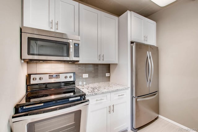 444 17th St Unit 701, Denver, CO 80202 - kitchen with stainless steel appliances, tasteful backsplash, white cabinets, light stone counters, and baseboards
