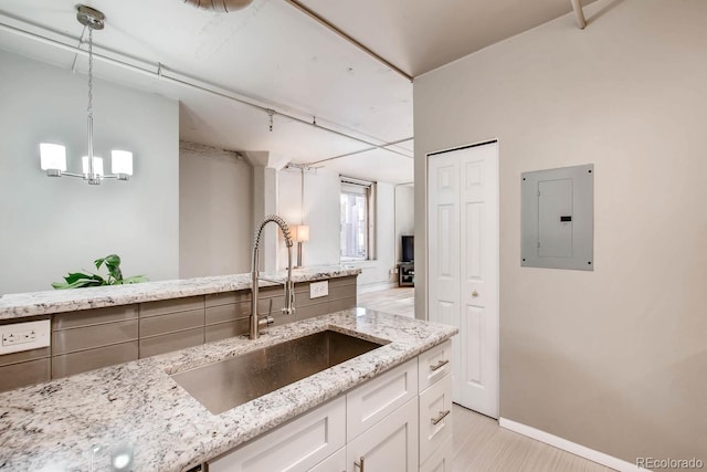 444 17th St Unit 701, Denver, CO 80202 - kitchen featuring a sink, electric panel, white cabinetry, light stone counters, and hanging light fixtures