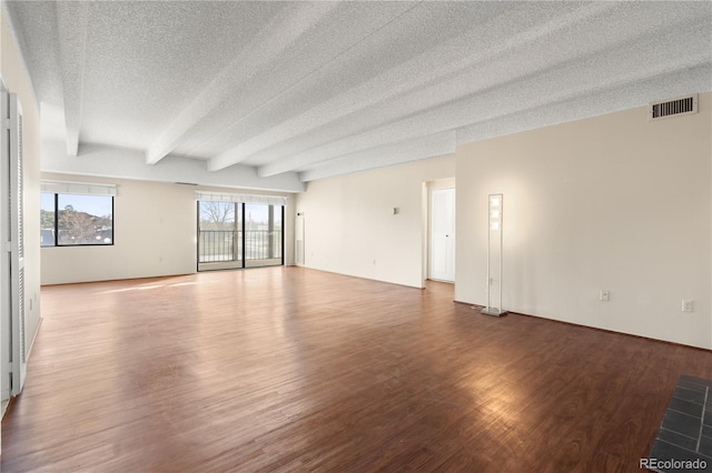 unfurnished room featuring beamed ceiling, wood-type flooring, and a textured ceiling