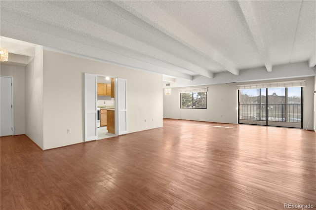 spare room featuring beam ceiling, a textured ceiling, and light wood-type flooring