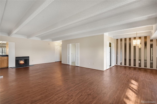 unfurnished living room with dark hardwood / wood-style flooring, beam ceiling, a chandelier, and a textured ceiling