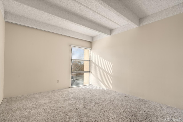 unfurnished room featuring beamed ceiling, carpet floors, and a textured ceiling