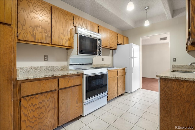 kitchen featuring pendant lighting, sink, white appliances, light tile patterned floors, and a textured ceiling