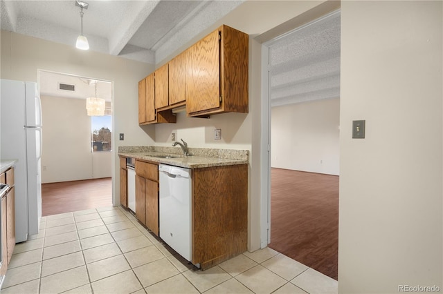 kitchen with sink, a textured ceiling, light tile patterned floors, pendant lighting, and white appliances