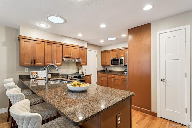 kitchen featuring sink, a breakfast bar, dark stone counters, stainless steel appliances, and kitchen peninsula