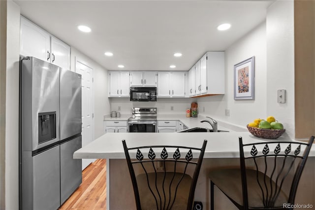 2181 E Phillips Ln, Centennial, CO 80122 - kitchen with appliances with stainless steel finishes, a peninsula, recessed lighting, light countertops, and light wood-type flooring