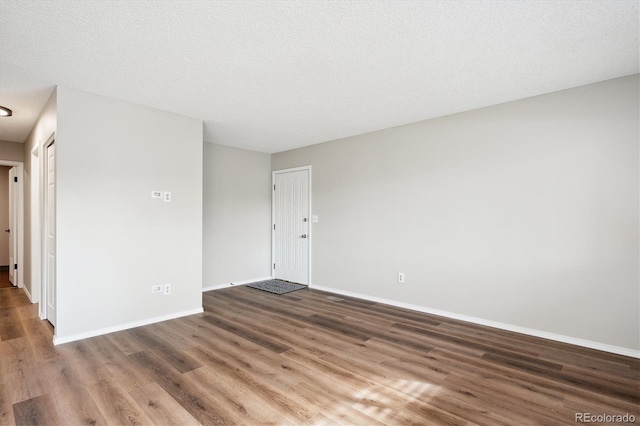 unfurnished room featuring dark wood-type flooring and a textured ceiling