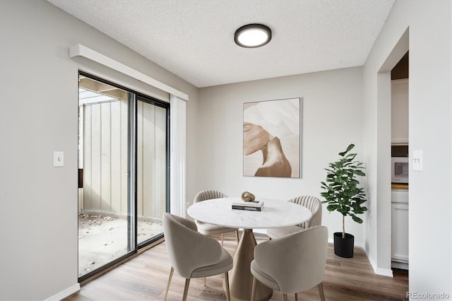 dining area featuring a wealth of natural light, a textured ceiling, and light hardwood / wood-style floors