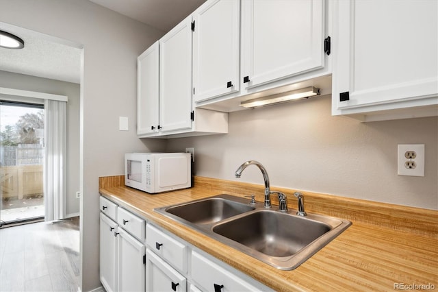 kitchen featuring sink, a textured ceiling, and white cabinets