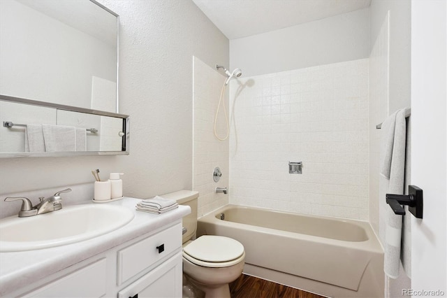 full bathroom featuring tiled shower / bath combo, vanity, hardwood / wood-style floors, and toilet