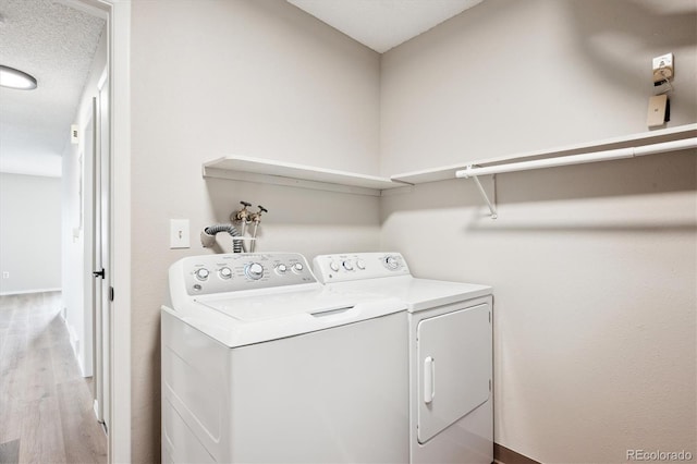 washroom with washing machine and dryer and light hardwood / wood-style flooring