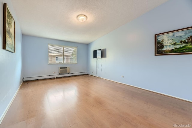 empty room featuring a textured ceiling, light hardwood / wood-style floors, an AC wall unit, and baseboard heating