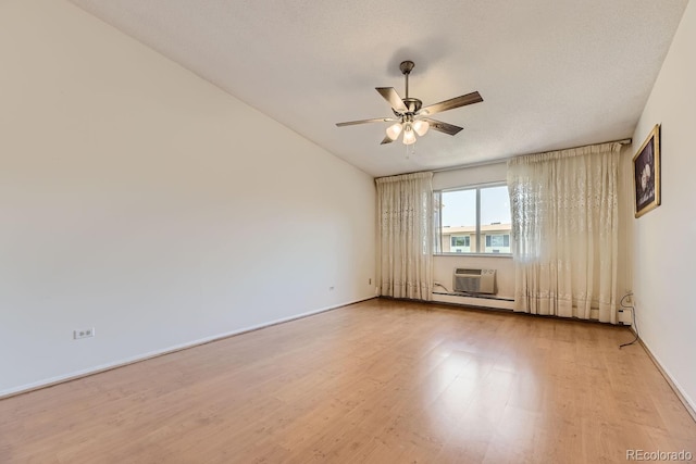 empty room with a baseboard heating unit, ceiling fan, light wood-type flooring, a textured ceiling, and a wall unit AC