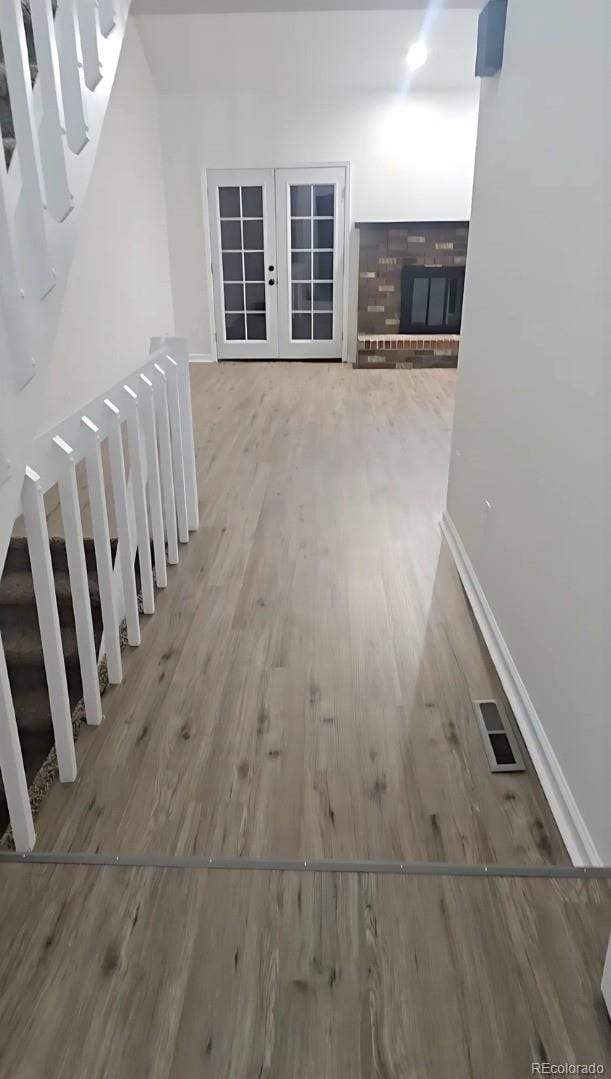 hall with light hardwood / wood-style floors and french doors