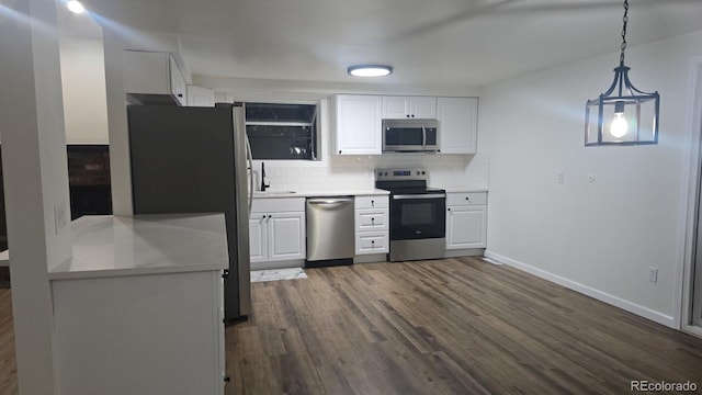 kitchen featuring decorative backsplash, appliances with stainless steel finishes, decorative light fixtures, dark hardwood / wood-style flooring, and white cabinetry