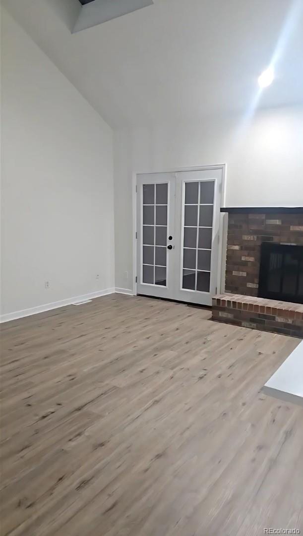 unfurnished living room with light hardwood / wood-style floors, a fireplace, and french doors