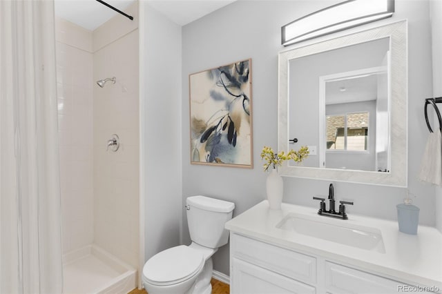 bathroom with a tile shower, vanity, and toilet