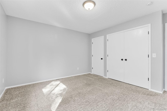 unfurnished bedroom featuring light colored carpet, a textured ceiling, and a closet