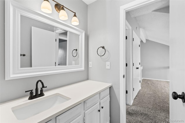 bathroom featuring a textured ceiling, vanity, and vaulted ceiling