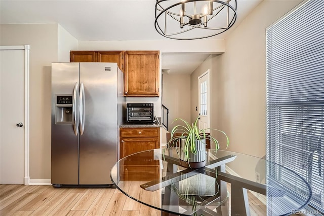 kitchen featuring brown cabinets, light wood-style flooring, an inviting chandelier, stainless steel fridge with ice dispenser, and a toaster