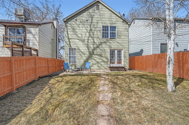 back of property with a fenced backyard, a yard, french doors, and entry steps