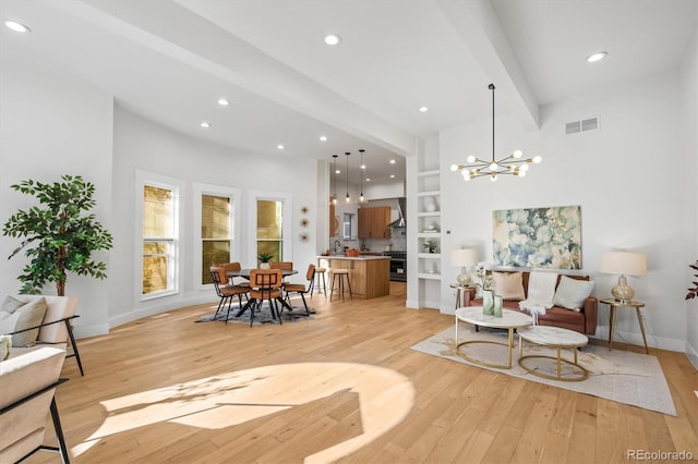 living room featuring an inviting chandelier, light hardwood / wood-style floors, and beam ceiling