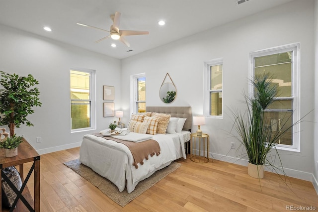 bedroom featuring ceiling fan, multiple windows, and light hardwood / wood-style flooring