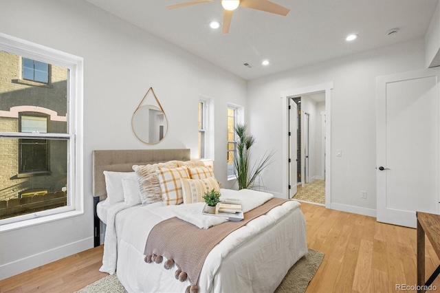 bedroom featuring ceiling fan, light hardwood / wood-style floors, and multiple windows