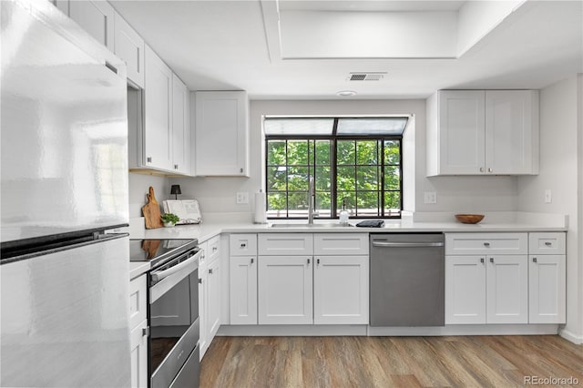 kitchen featuring stainless steel appliances, light countertops, light wood-style flooring, and white cabinets