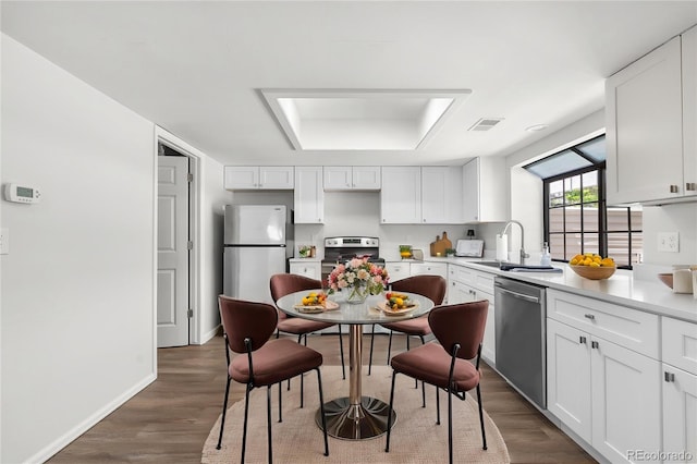 kitchen with appliances with stainless steel finishes, white cabinetry, dark wood-style flooring, and a sink