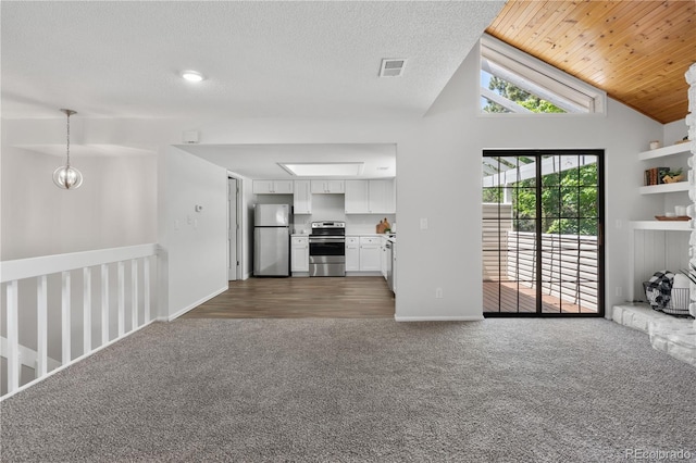 unfurnished living room featuring dark colored carpet, vaulted ceiling, attic access, and baseboards