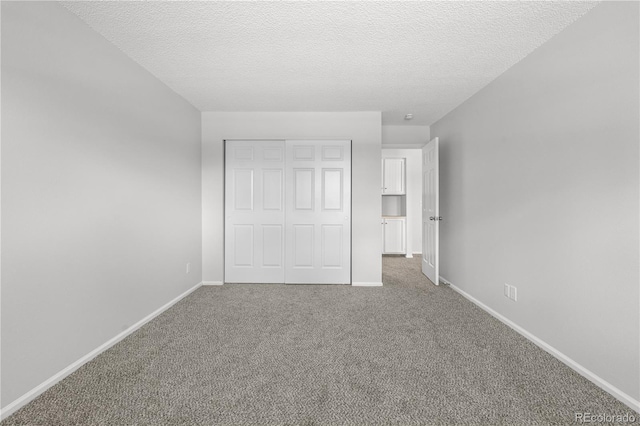unfurnished bedroom with a closet, carpet flooring, baseboards, and a textured ceiling