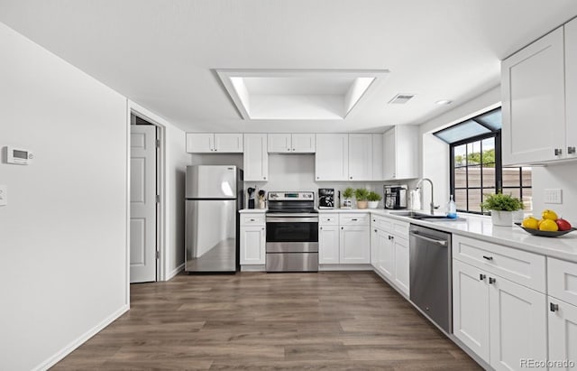 kitchen with stainless steel appliances, a raised ceiling, white cabinetry, a sink, and dark wood-style floors