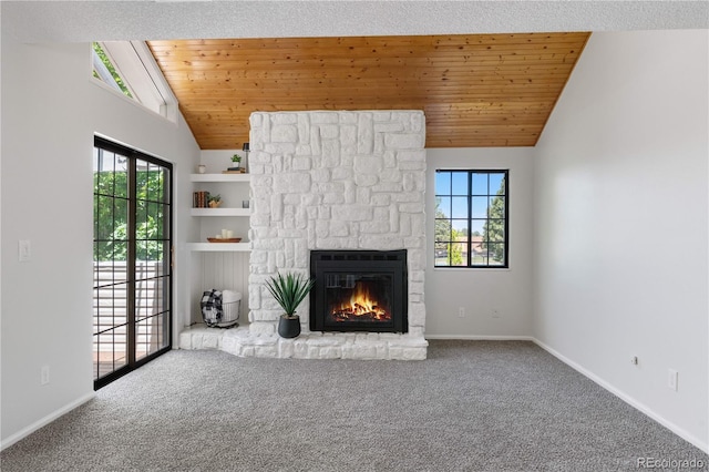unfurnished living room with vaulted ceiling, plenty of natural light, a stone fireplace, carpet, and wooden ceiling