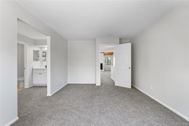 empty room featuring carpet, a textured ceiling, and baseboards