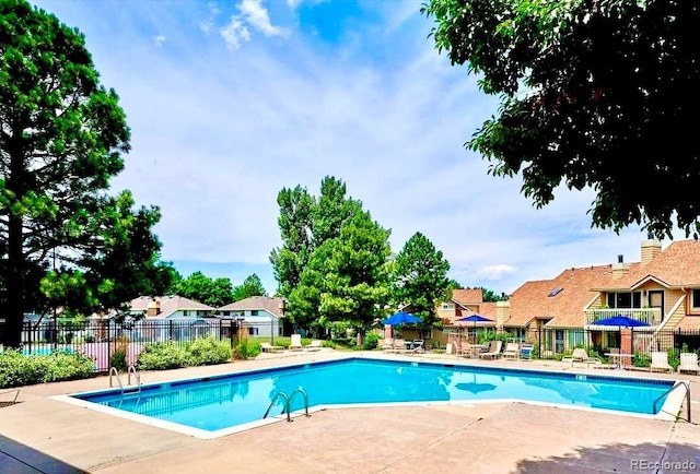 community pool featuring fence, a residential view, and a patio