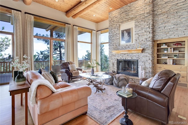 living room with beamed ceiling, wood finished floors, a fireplace, wood ceiling, and a towering ceiling