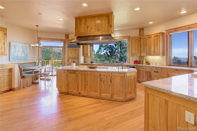 kitchen with decorative light fixtures, range hood, recessed lighting, light wood finished floors, and light stone countertops