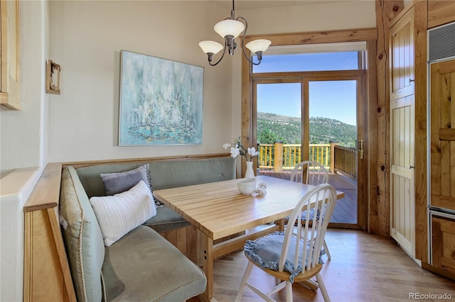 dining room featuring breakfast area, a mountain view, a chandelier, and light wood finished floors