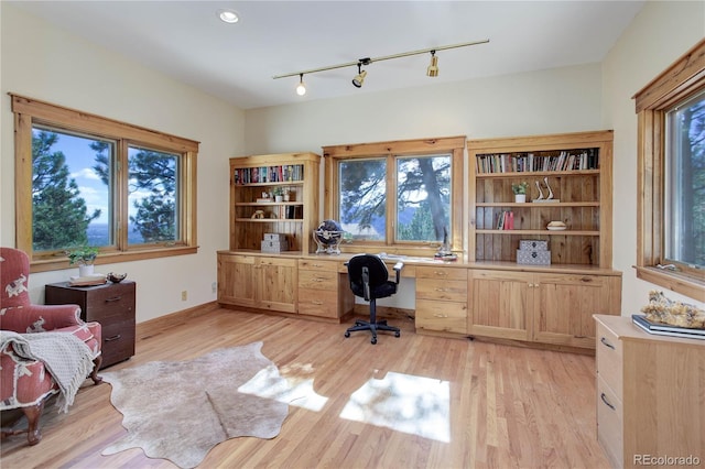 home office with track lighting, built in study area, light wood-type flooring, and baseboards