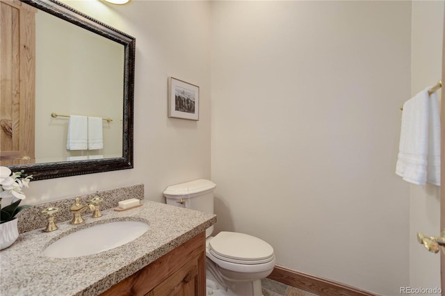 half bathroom with toilet, vanity, and baseboards