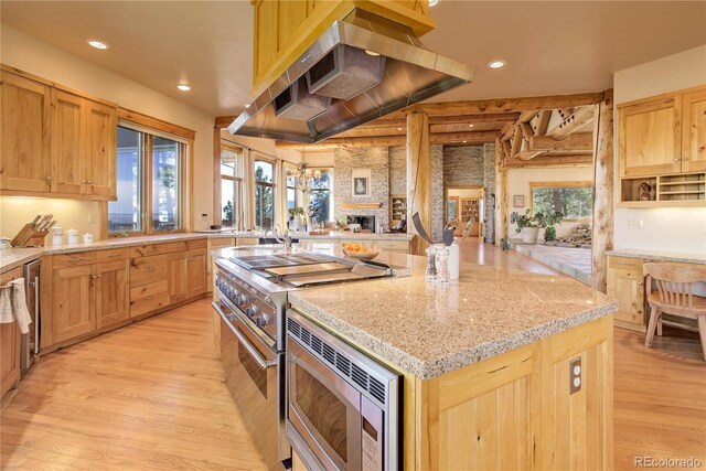 4440 Monitor Rock Ln, Colorado Springs, CO 80904 - kitchen featuring appliances with stainless steel finishes, a center island, wall chimney range hood, light wood-type flooring, and recessed lighting